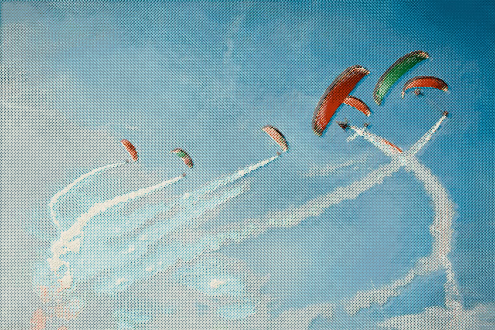 Paragliders trailing smoke across a cyan sky